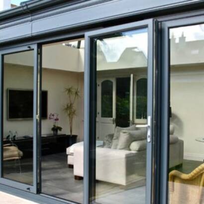 Grey aluminium bi-fold doors partially open onto a living room